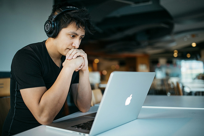 Man wearing headphones, focused on laptop, possibly preparing for an IT interview using AI.