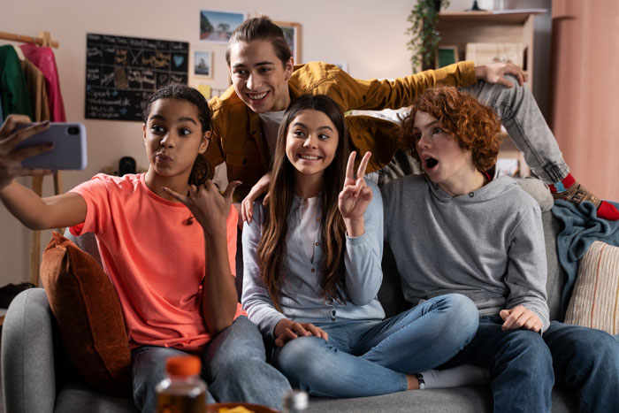 Group of teens taking a selfie together at home, depicting friendship before a teen suffers allergic reaction at a friend's house.